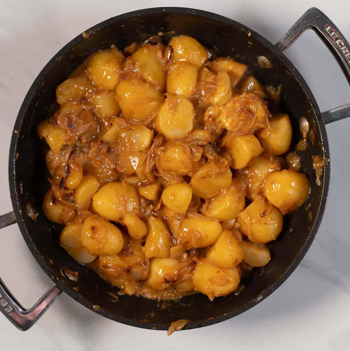 Savory glazed onions and potatoes simmering in a skillet.