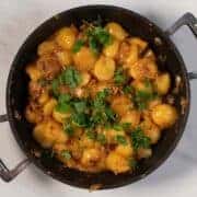 Creamy French onion potatoes with parsley garnish in a skillet.