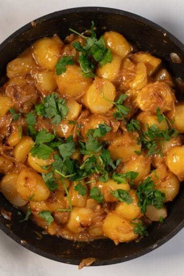 Creamy French onion potatoes with parsley garnish in a skillet.