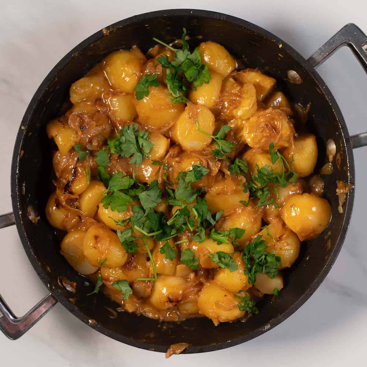 Creamy French onion potatoes with parsley garnish in a skillet.