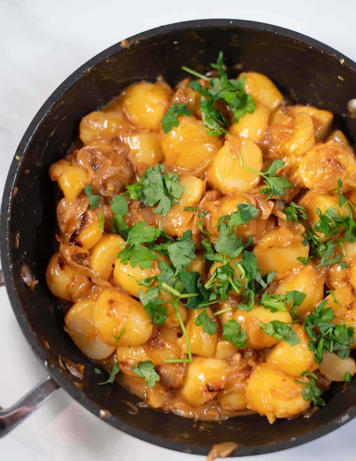 Creamy potatoes with caramelized onions and fresh parsley in a skillet.