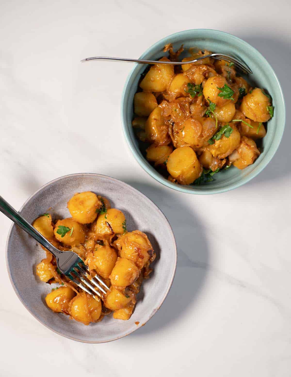 Creamy onions potatoes dish served in bowls with herbs.