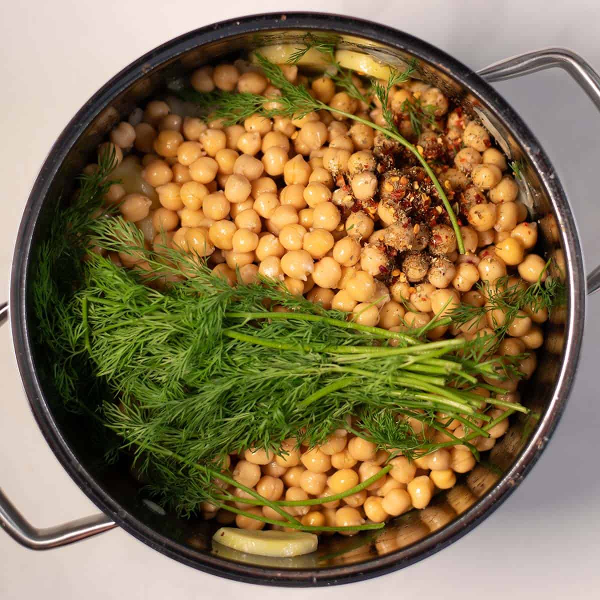 Cooked chickpeas with fresh dill and spices in a pot for Greek Revithia soup.