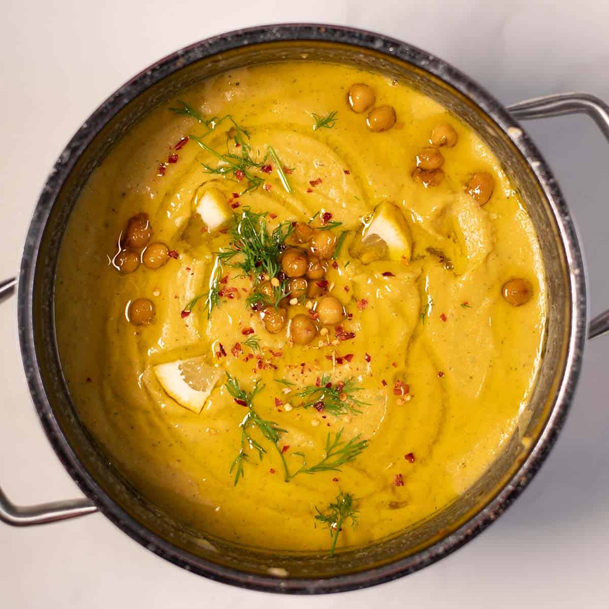 Creamy Greek chickpea soup garnished with herbs and spices.