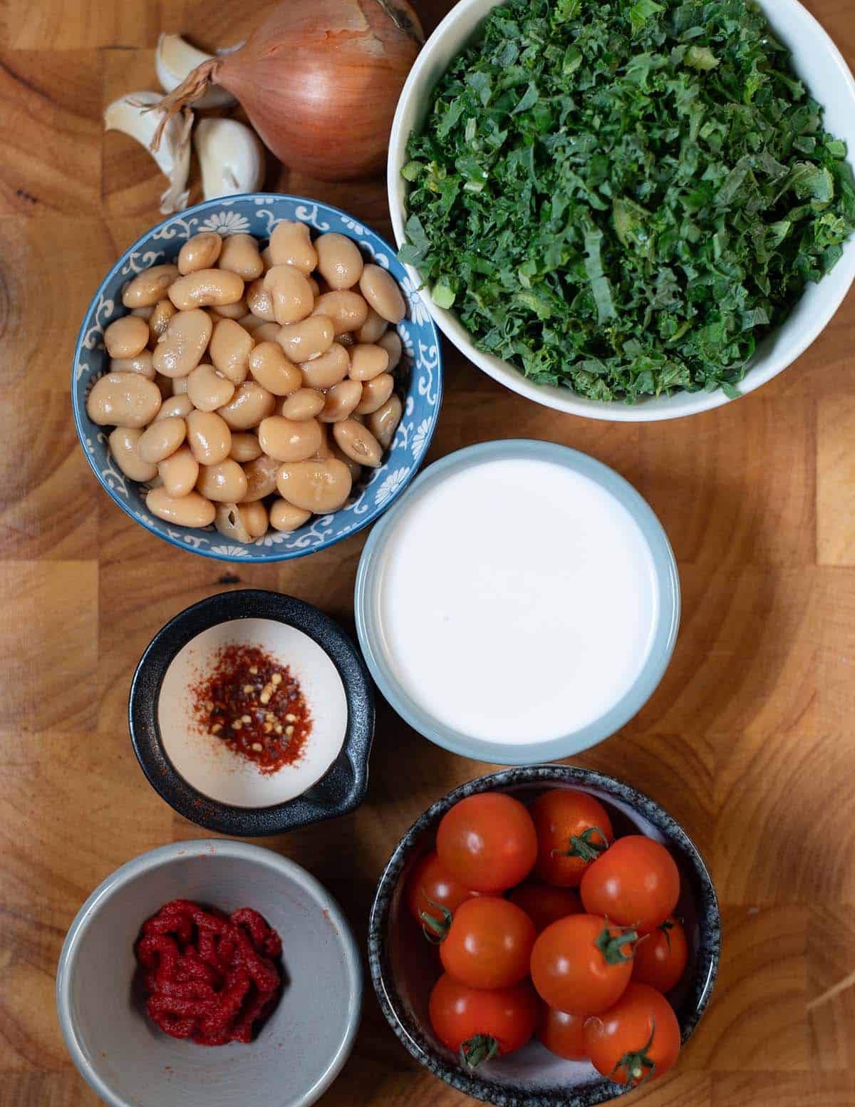 Fresh kale, white beans, cherry tomatoes, garlic, and spices for a healthy dish.