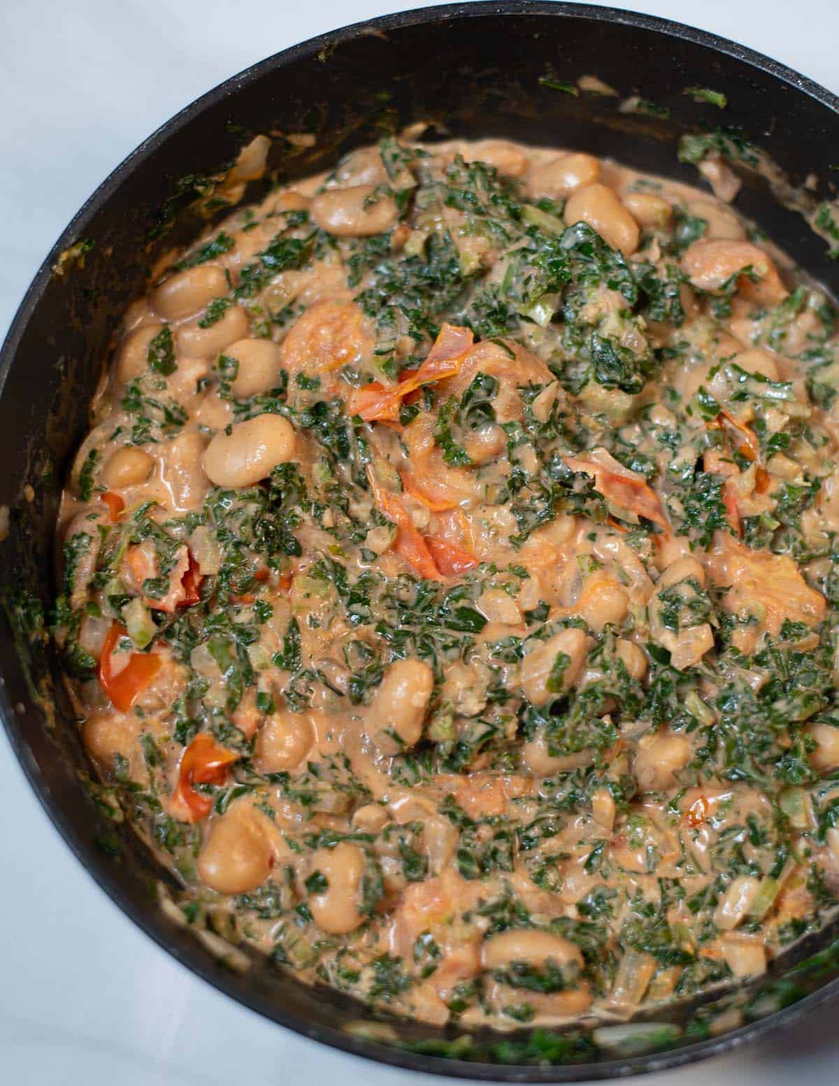 Creamy Tuscan kale and white beans in a skillet, ready to serve.