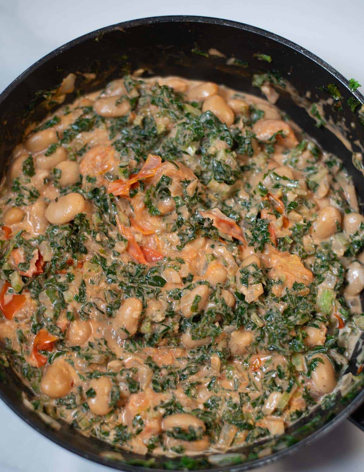 Creamy kale and white beans in a skillet, ready to serve.